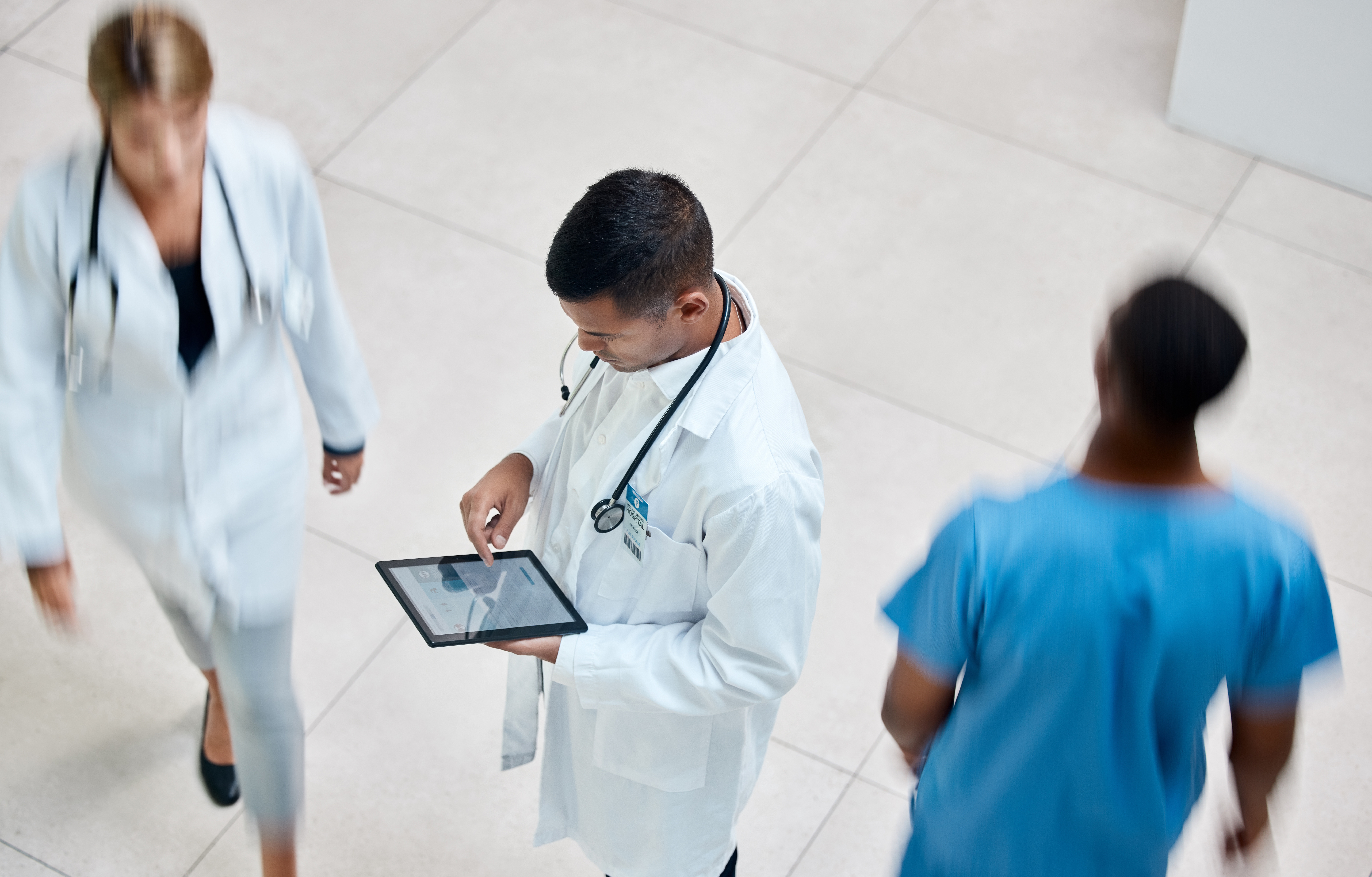 Tablet, healthcare and medicine with a man doctor working in a busy hospital with urgency
